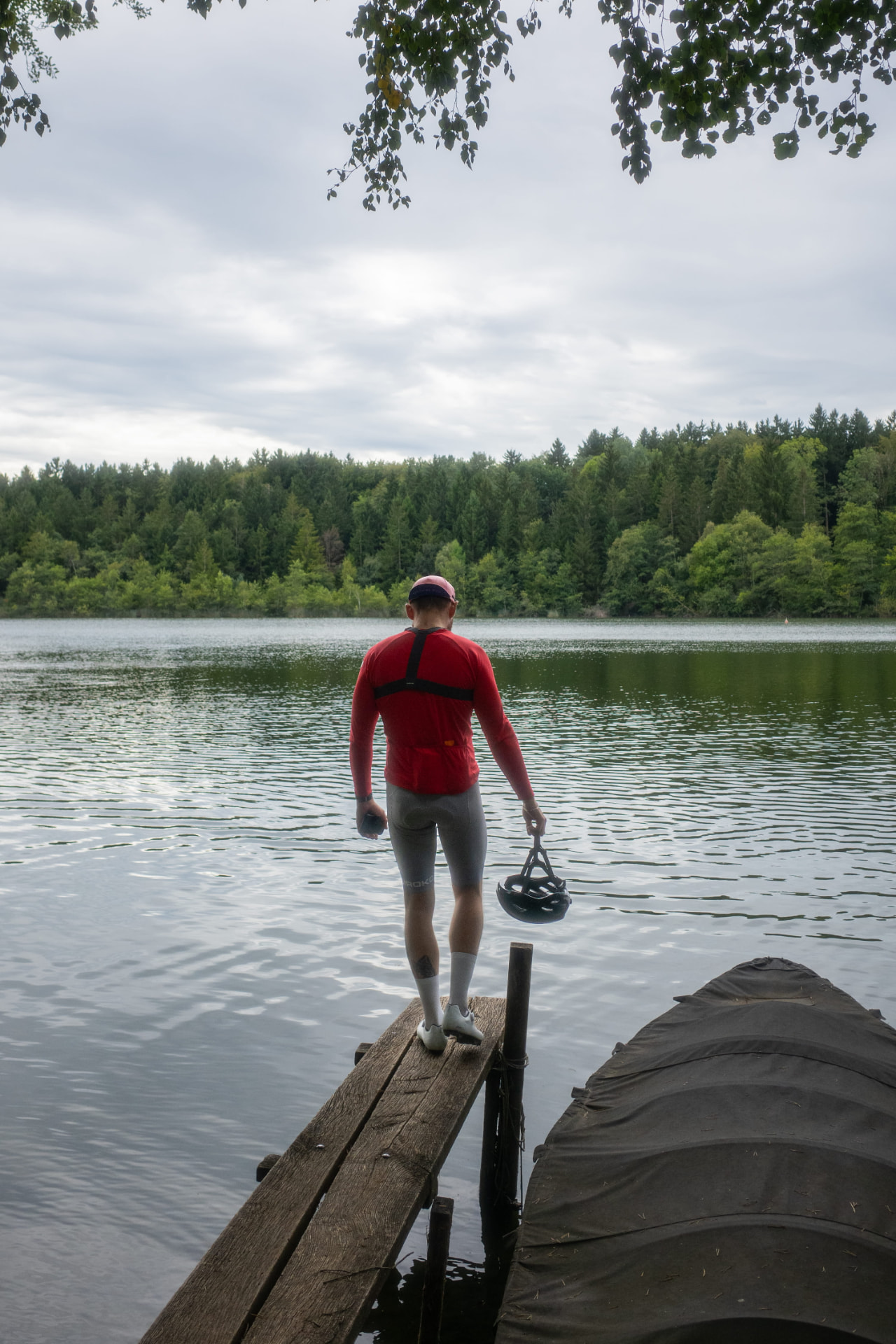 Fahrer steht mit Helm am Steg eines Sees